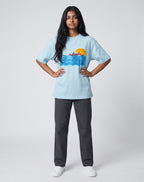 Sunset Boat graphic t-shirt on BABY BLUE unisex 100% cotton crew neck, vibrant high-quality serene sunset boat scene, artistic flair beach design, DTG print 300 DPI, 180 GSM breathable soft fabric