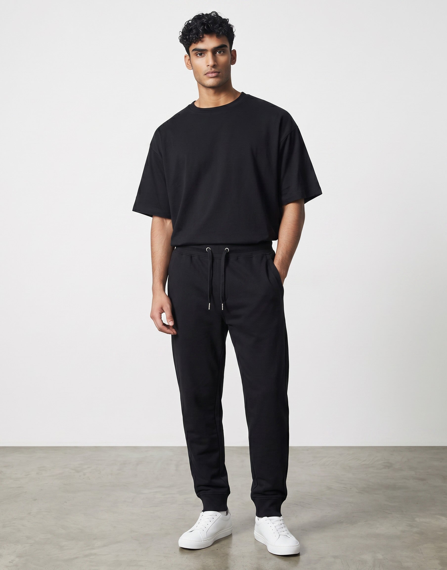 A man wearing Tribe Neo 91 black cotton fleece joggers with a drawstring waist and ribbed cuffs in a regular fit.