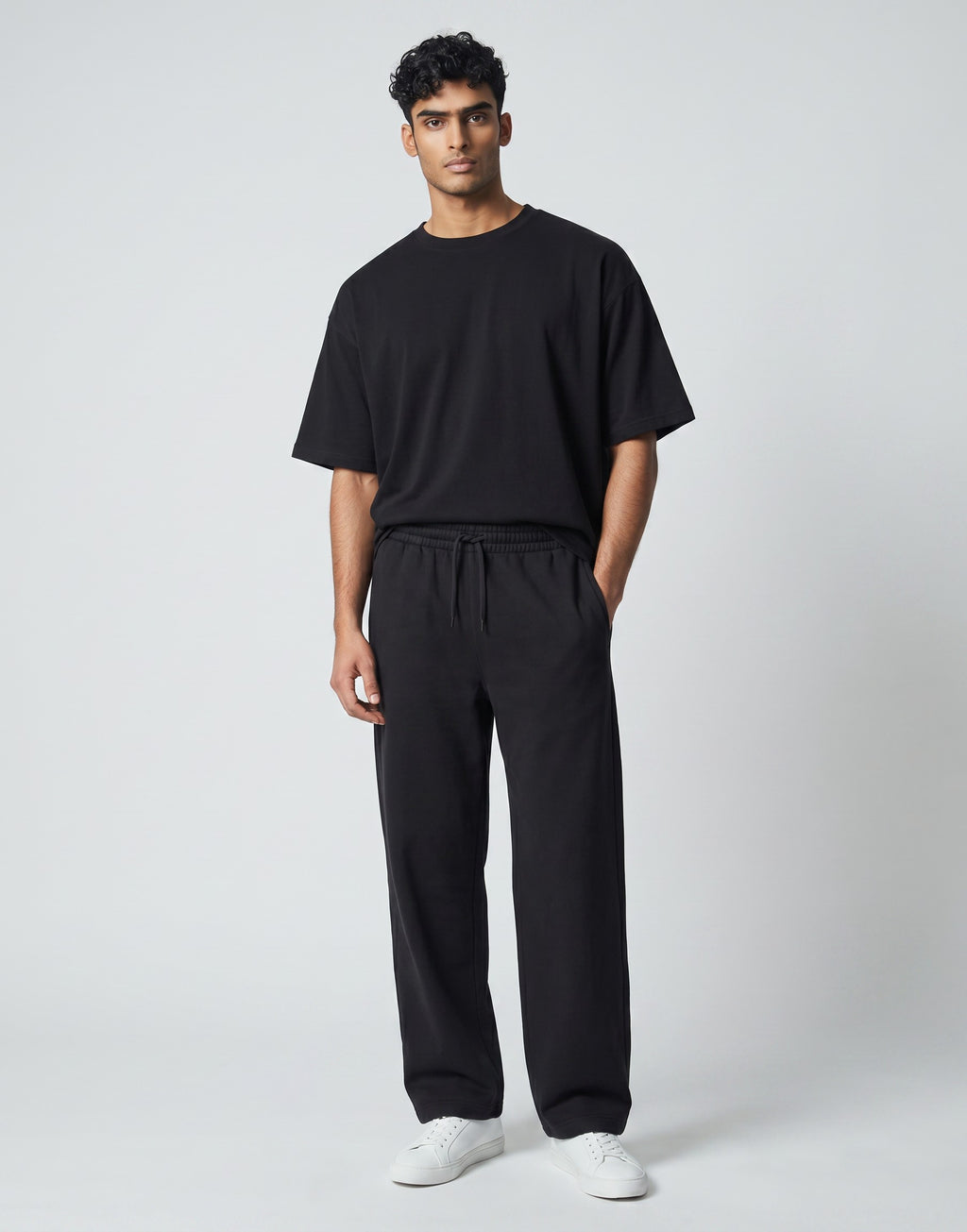 Male model wearing Tribe Neo 91 black wide-leg cotton sweatpants with an elastic drawstring waist and front pockets.