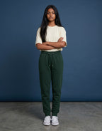 A woman wearing Tribe Neo 91 bottle green cotton fleece joggers with a ribbed waistband and tapered leg cuffs.