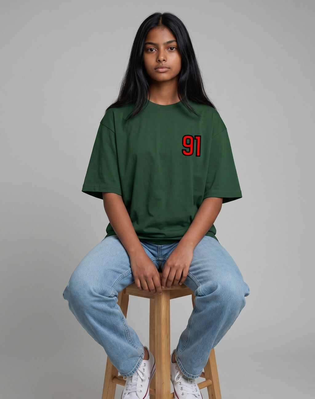 Tribe Neo 91 unisex oversized green cotton t-shirt with red and black 91 chest print worn by a model on a stool.