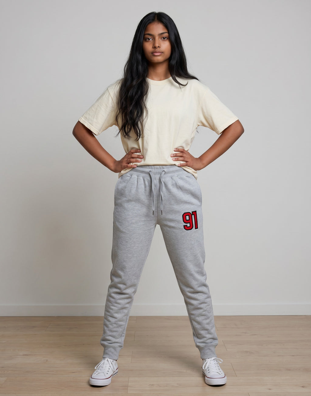 Tribe Neo 91 unisex grey cotton fleece joggers with red 91 graphic on thigh, worn by a woman with a cream t-shirt.