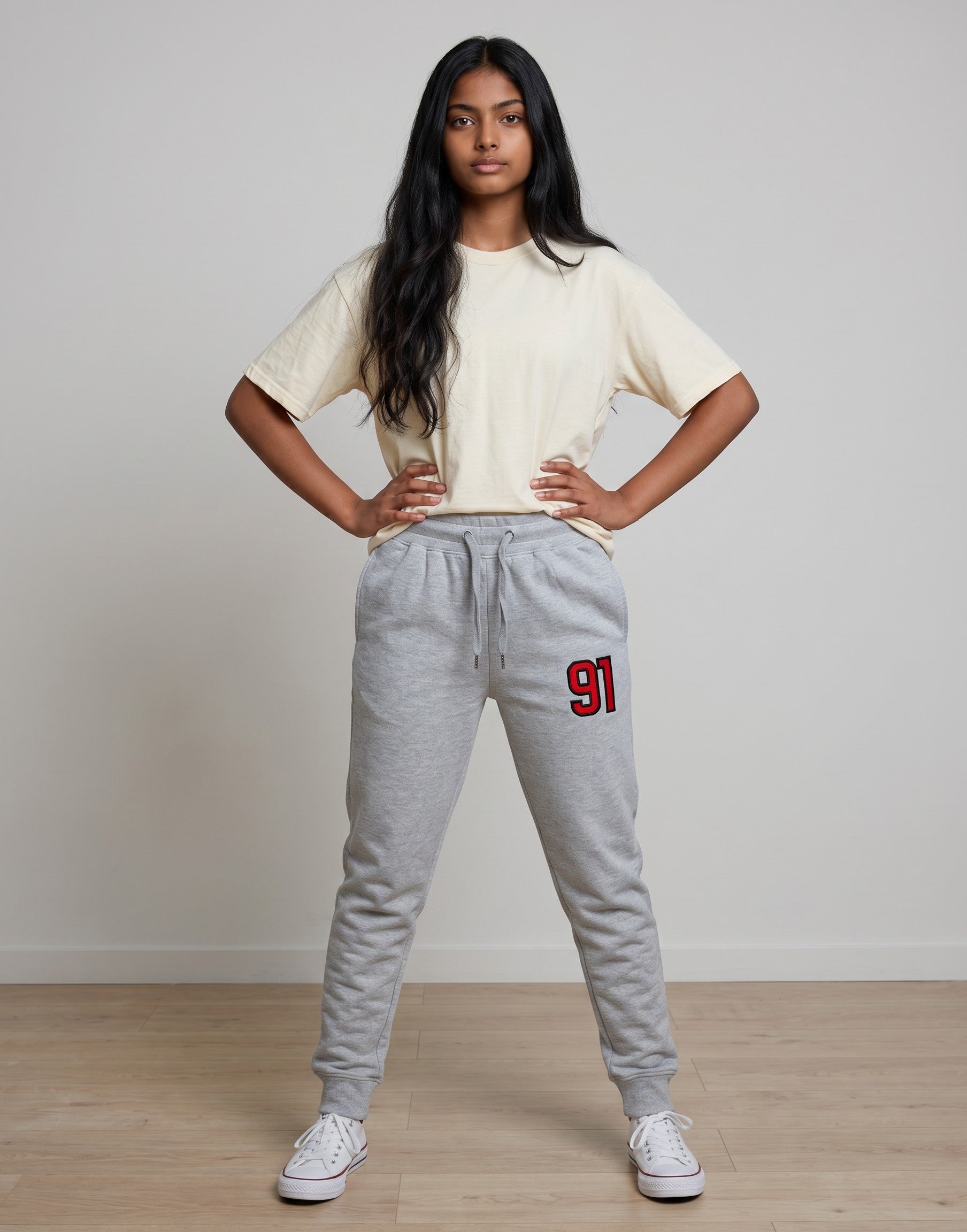 Tribe Neo 91 unisex grey cotton fleece joggers with red 91 graphic on thigh, worn by a woman with a cream t-shirt.