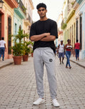 Tribe Neo 91 grey melange cotton fleece joggers with yin yang graphic on thigh worn by a man on a cobblestone street
