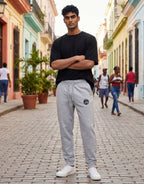 Tribe Neo 91 grey melange cotton fleece joggers with yin yang graphic on thigh worn by a man on a cobblestone street
