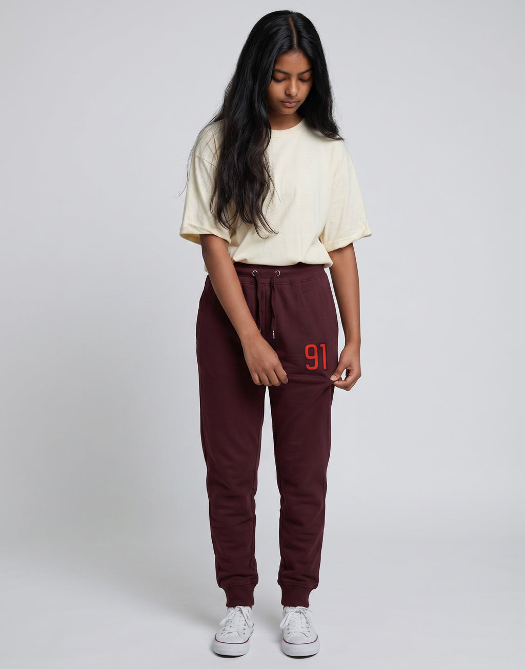 Model wearing Tribe Neo 91 maroon cotton fleece joggers with a red 91 graphic on the thigh and ribbed cuffs.