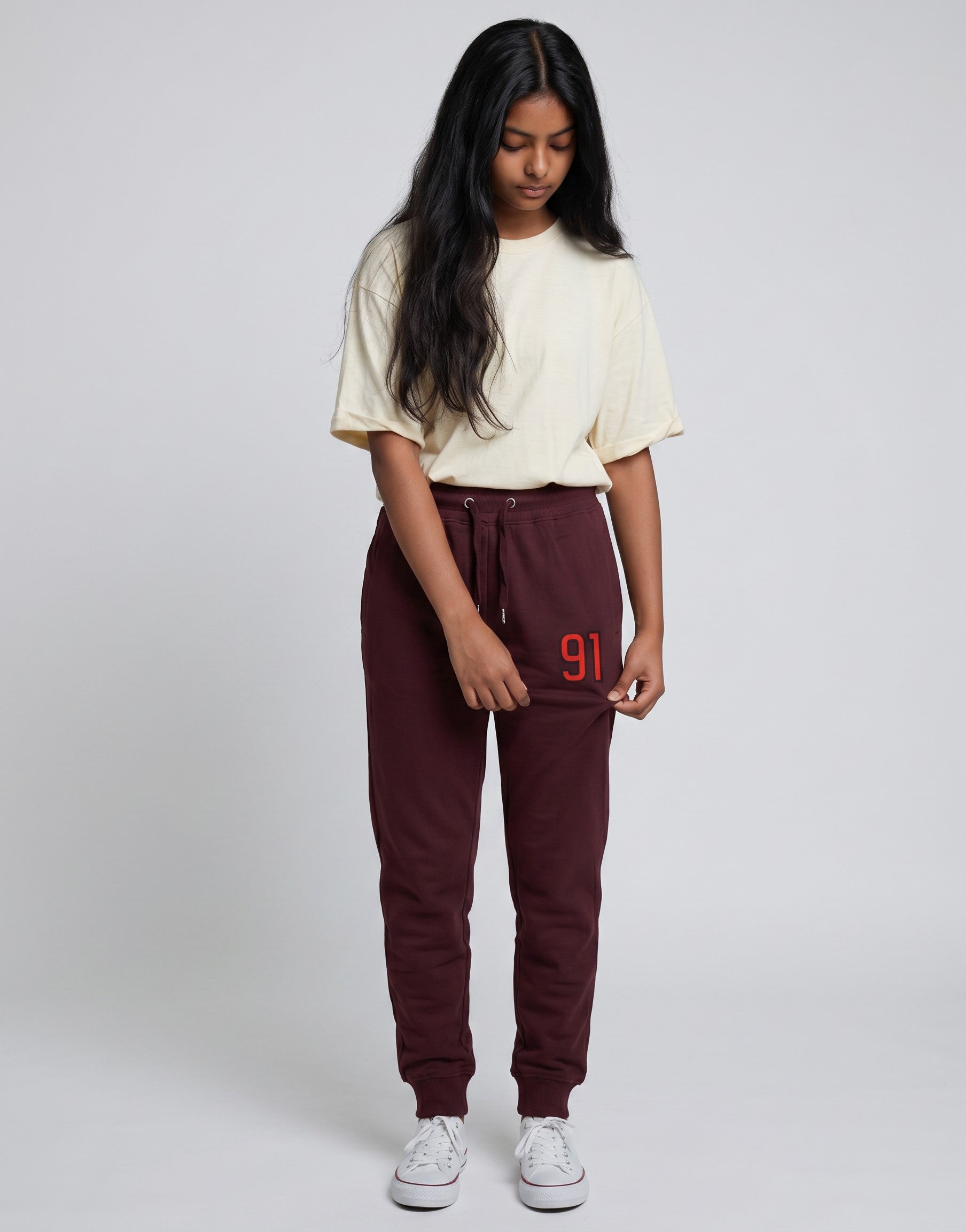 Model wearing Tribe Neo 91 maroon cotton fleece joggers with a red 91 graphic on the thigh and ribbed cuffs.