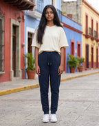 A model wearing Tribe Neo 91 navy blue unisex everyday joggers with a ribbed waistband and tapered cuffs on a street.