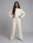 A model wearing Tribe Neo 91 off-white wide-leg cotton sweatpants and matching sweatshirt with an elastic drawstring.