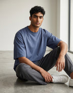 A male model wearing a Tribe Neo 91 unisex oversized petrol blue heavyweight cotton t-shirt with dropped shoulders.
