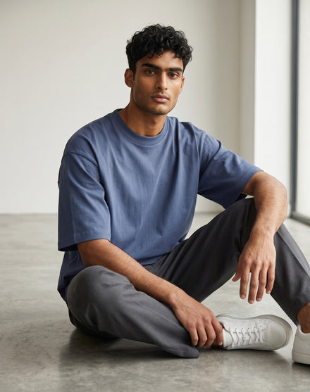 A male model wearing a Tribe Neo 91 unisex oversized petrol blue heavyweight cotton t-shirt with dropped shoulders.
